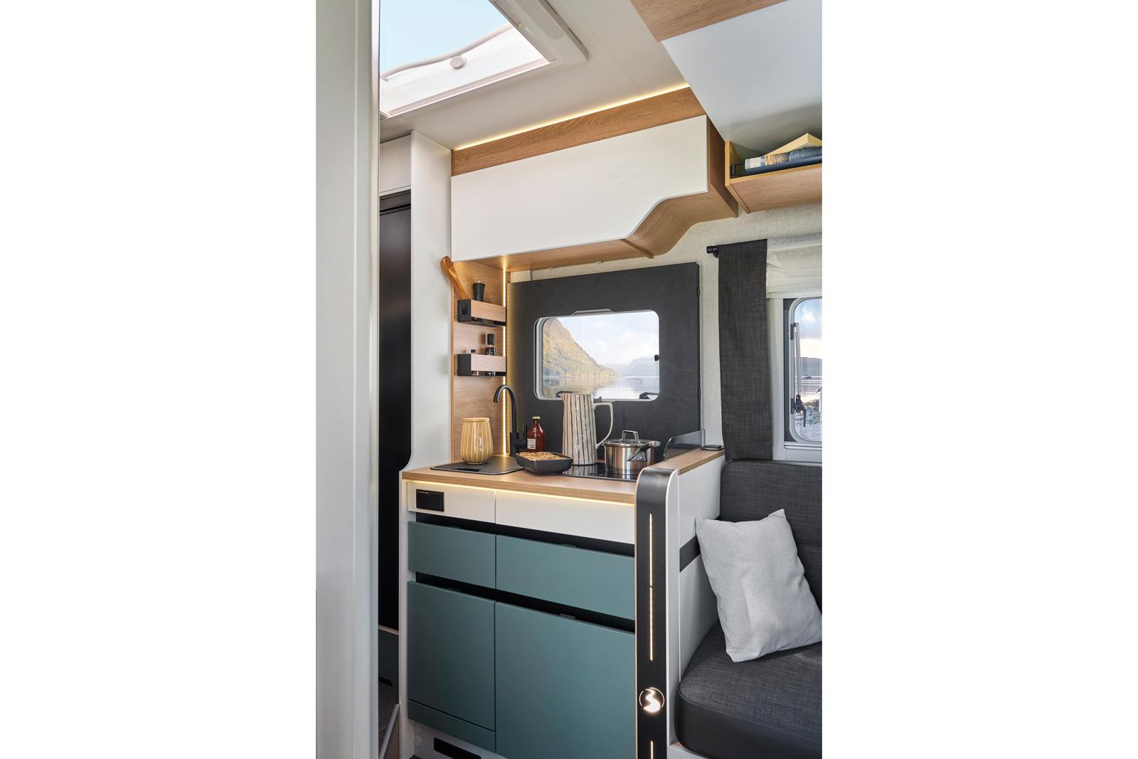 Bavaria Qwest 630G. La cuisine est compacte mais rien ne manque : plaque de cuisson 2 feux à gaz, couvercle d'évier pour agrandir le plan de travail, nombreux rangements intelligents… et grand frigo de l'autre côté du couloir.
