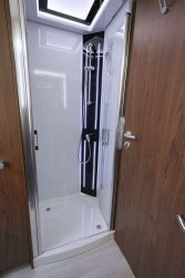 Bac polyester et parois de douche en verre Securit. Pas de lanterneau directement au-dessus de la douche, mais entre les deux espaces douche et WC.